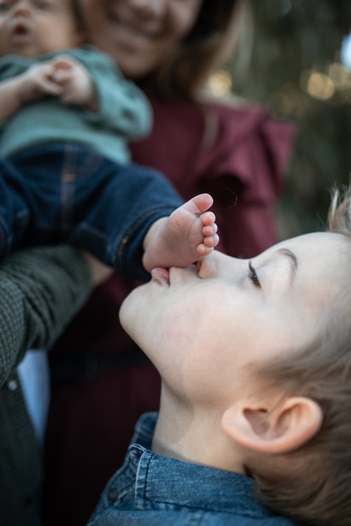 Heartwarming moment of a young boy affectionately kissing a baby's foot, capturing sibling love.